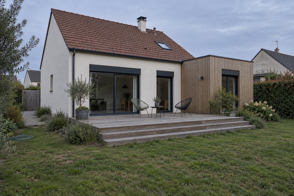 Maison des années 1980 rénovée avec enduit clair, extension bardée de bois et grande terrasse en bois